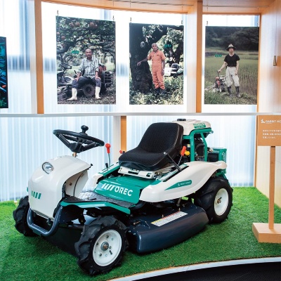 オーレック本社のエントランスには広いスペースが設けられ、来客者を迎え入れるように製品が展示されている。車体の色は、リブランディングの際にコンセプトモデルをつくり、ロゴと同じ緑色にそろえた。中央は2019年度グッドデザイン賞に選ばれた水田除草機「WEED MAN」(写真/林田大輔)