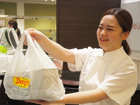 デニーズの宅配専用厨房で調理した料理を配送用の袋に入れて、宅配事業者のスタッフに手渡す