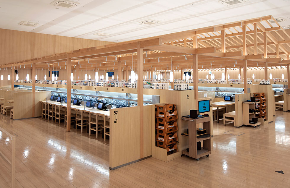 くら寿司「浅草ROX店」の内部。店内に支柱や屋根からなる「やぐら」を組み、その下にカウンターやテーブル、椅子、パーティション、回転寿司の搬送装置をバランスよく配置した。やぐらによる木の味わいがある（写真／丸毛 透）