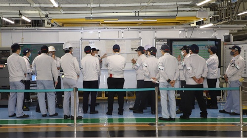 あらゆる部署の目標や進捗の数字などの情報が詰まった日常管理板の前で、議論をする光景