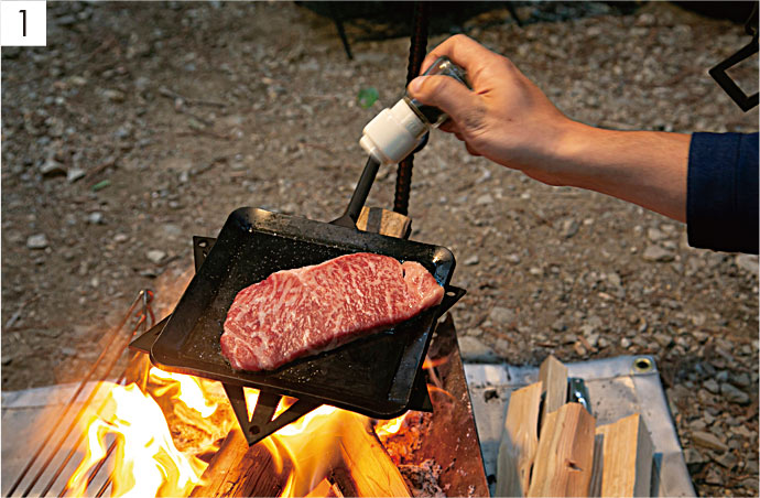 【1】たき火台の上に鉄板を設置して、ステーキを載せて焼く