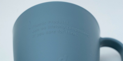 プラスチックマグカップの表面には「Plastic Products can be lifelong companions if you care for them.（プラスチック製品であっても、一生モノになり得ます。あなたが大切にすればね。）」というメッセージが刻印されている