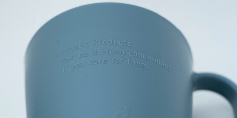 プラスチックマグカップの表面には「Plastic Products can be lifelong companions if you care for them.(プラスチック製品であっても、一生モノになり得ます。あなたが大切にすればね。)」というメッセージが刻印されている