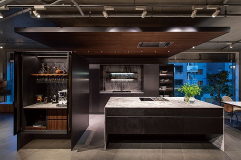 リネアタラーラのショールームに展示しているキッチンの一つ。天板は天然の大理石で、木材の扉の表面には金属調の塗装を施している。左手の棚は、ホテルの客室にあるカフェコーナーをイメージしたキャビネット。リビングとキッチンの合間に設置することで、来客が気軽にコーヒーを入れたり、ホテルライクな生活が楽しめたりするようにデザインした