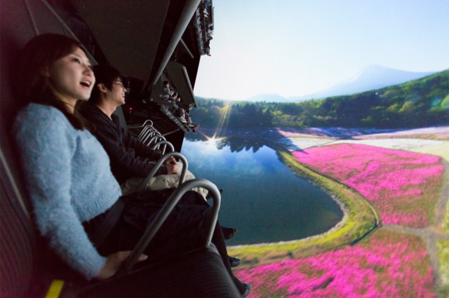 14年に開設した「富士飛行社」は巨大スクリーンに映し出された富士山周辺上空の映像と動くシートで富士山上空を飛んでいるかのような体験ができるアトラクション。これまでは団体客に限定し、入園料を徴収せずにアトラクション料金だけで楽しめるようにしてきた