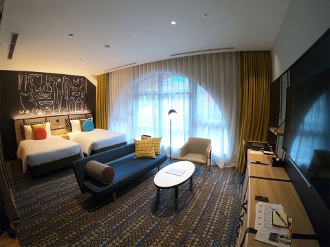 客室の壁面は洋服の型紙をイメージしたデザイン。一部の客室には、外観の特徴であるアーチ状の窓がある