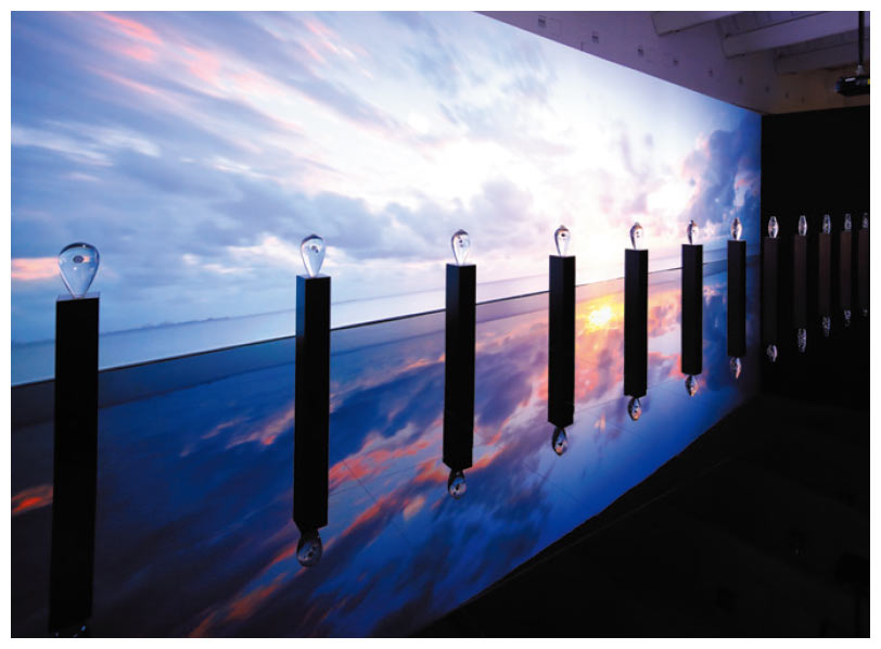 ミラノサローネでの展示「THE FLOW OF TIME」。形状の異なる12体の透明なオブジェに、200以上からなるスプリングドライブの時計部品を封入。オブジェの背後には、太陽や天体の軌道、舞い散る花びら、水紋などの映像を投映し、時の移ろいを表現している。DSA日本空間デザイン賞2018金賞およびSDA賞（第52回日本サインデザイン賞）銀賞を受賞。2018年10月に東京・青山で凱旋展示を開催した他、今後海外にも巡回する予定　プロデュース:桐山登士樹氏／クリエイター:吉泉聡氏（TAKT PROJECT）、阿部伸吾氏