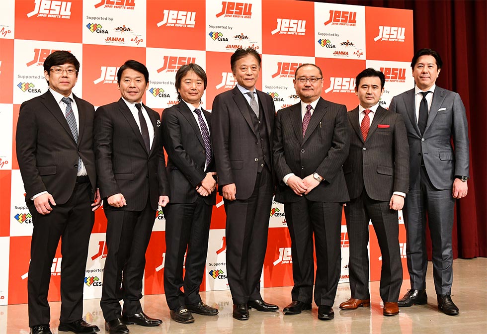 18年2月に発足したJeSU。写真は役員を務める7人。左からガンホー・オンライン・エンターテイメント取締役の越智政人氏、カプコン社長の辻本春弘氏、JeSU専務理事の平方彰氏、JeSU会長の岡村秀樹氏（セガホールディングス代表取締役社長）、JeSU副会長の浜村弘一氏（KADOKAWAデジタルエンタテインメント担当シニアアドバイザー）、SANKO社長の鈴木文雄氏、コナミデジタルエンタテインメント社長の早川英樹氏