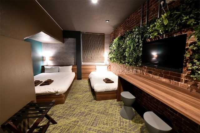 3人部屋 ダブルベッドの上にあるコンクリ 日経クロストレンド