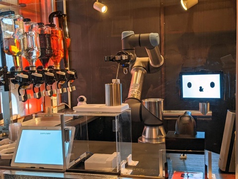 武骨な印象を受ける工業用ロボットの横には“顔”のディスプレー。笑ったり目を閉じたりする。酒類の提供には不要とも思えるが、“顔”があると失敗しても許してもらいやすいとのこと