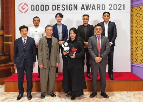 授賞式の様子。前列左から日本デザイン振興会理事長の深野弘行氏、2021年度グッドデザイン賞審査委員長の安次富隆氏、大賞を受賞したオリィ研究所の吉藤健太朗氏、審査副委員長の齋藤精一氏。後列は最終審査に残った4企業・団体の代表者