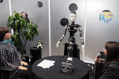 NTTの展示の目玉は、大阪大学の石黒浩教授がプロデュースするロボットと人間の自律的な会話のデモ。写真の中央だけでなく左もロボットで、右の人間と合わせて3人で自律的な会話を行っていた