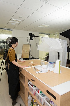 DELISH KITCHENの撮影の様子。作業台の真上にカメラが備え付けられていて、スタッフはディスプレーで映りを確認しながら一人で調理、撮影する。時には編集まで行うこともあるという