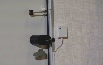 ドアノブの上に付いている黒い装置がスマートロック。壁に付いている白い正方形のデバイスがコミュニケーションカメラ
