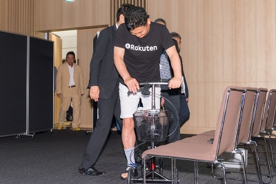 三木谷会長兼社長は足に包帯を巻いて、キックボードのような歩行を補助する器具に乗って登場