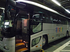 クラブツーリズムの専用バス。乗車する前に配られたのは、しおり、羽田空港と東京駅の構内地図のコピー、ツアー参加者用のバッジ。しおりには、今日のスケジュールのほか、ひとり旅の説明が書かれている。バッジの裏には添乗員の携帯電話番号が手書きされていた
