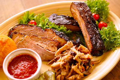 「トライスターBBQコンボプレート」(2808円)。写真手前から時計回りに、豚の肩から腕の大きな塊肉を手で割いたプルドポーク、牛の肩から下の部分にあたるブリスケット、スペアリブを盛り合わせている